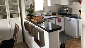 Une cuisine moderne avec des meubles blancs, un plan de travail noir et un lave-vaisselle encastré.