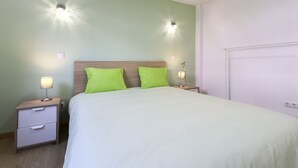 A neatly made bed with green pillows, two bedside lamps, and a nightstand with drawers. - Relaxing Guesthouse - Sónia's Houses (Lisbon)