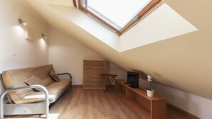 A modern loft bedroom with a sloped ceiling, a sofa bed, a wooden bench, a small table, and a potted plant. - Relaxing Guesthouse - Sónia's Houses (Lisbon)