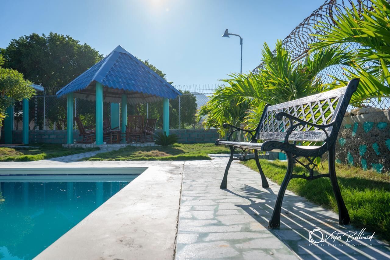 A poolside area with a bench, a gazebo, and a fence.