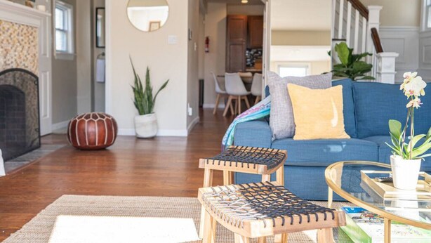 Una sala de estar con un sofá azul, una mesa de centro de madera y un tapete estampado.