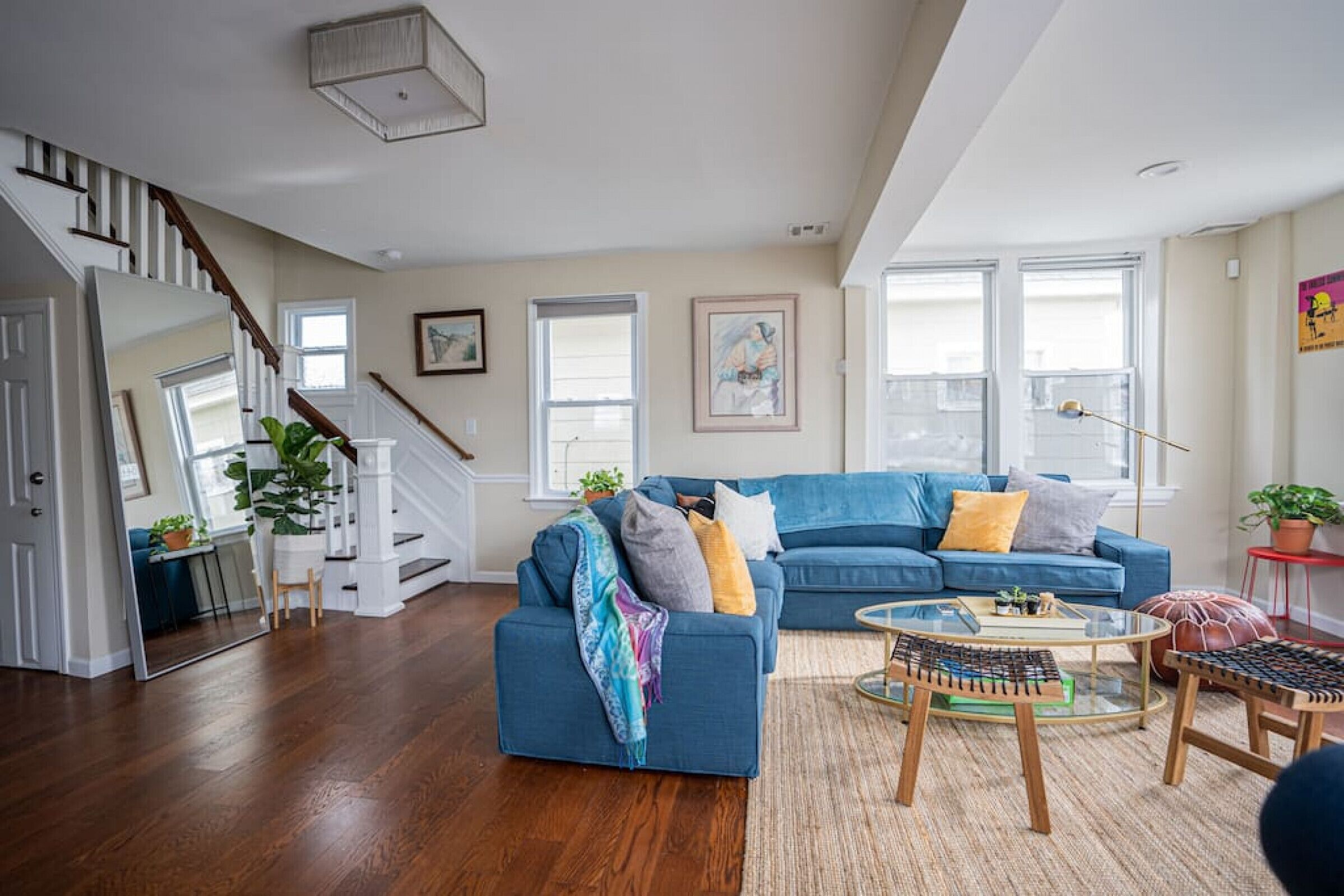 Amplia sala de estar con un sofá azul, una mesa de centro y una escalera que conduce a un piso superior.