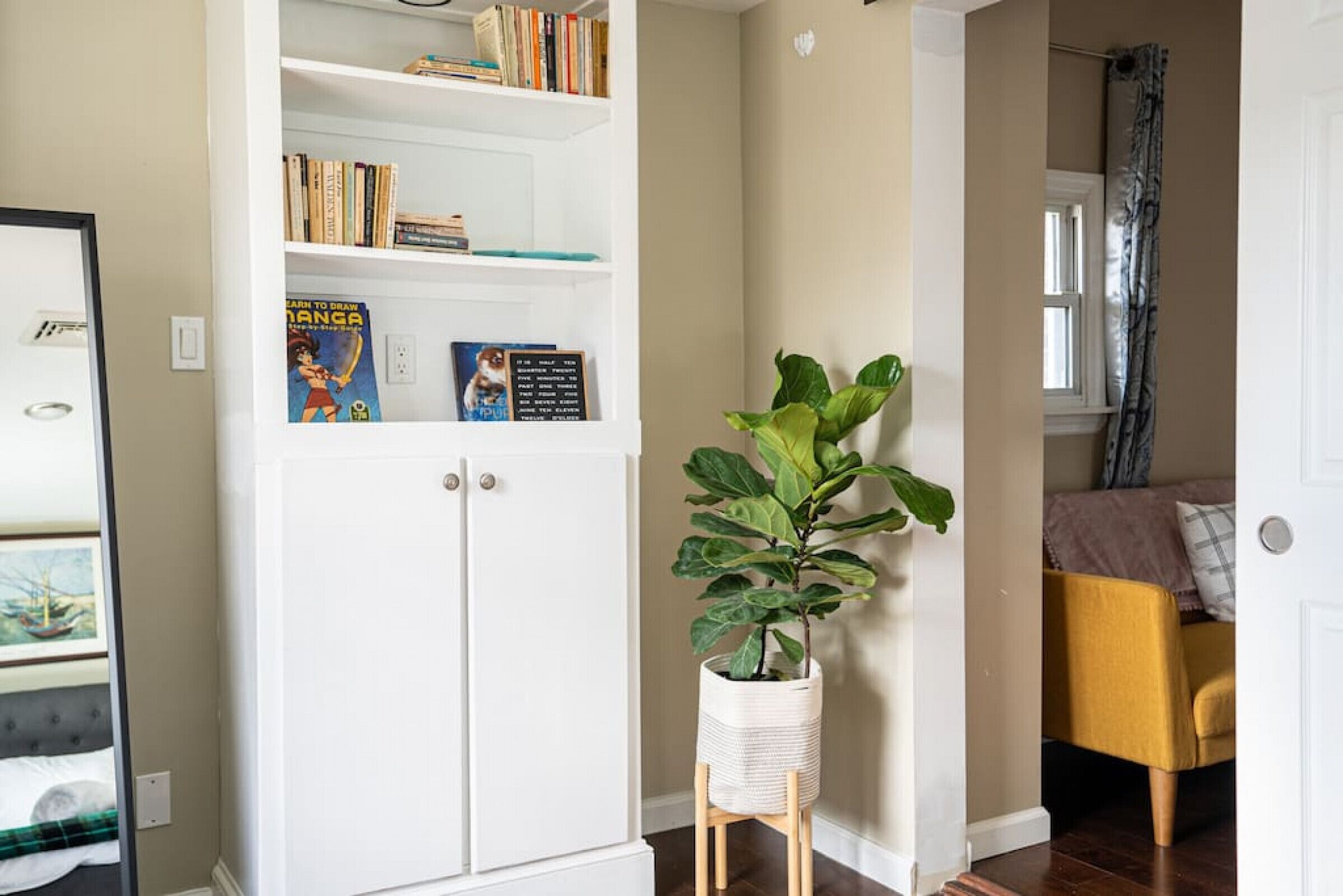 Un aparador blanco con libros y una planta en maceta.