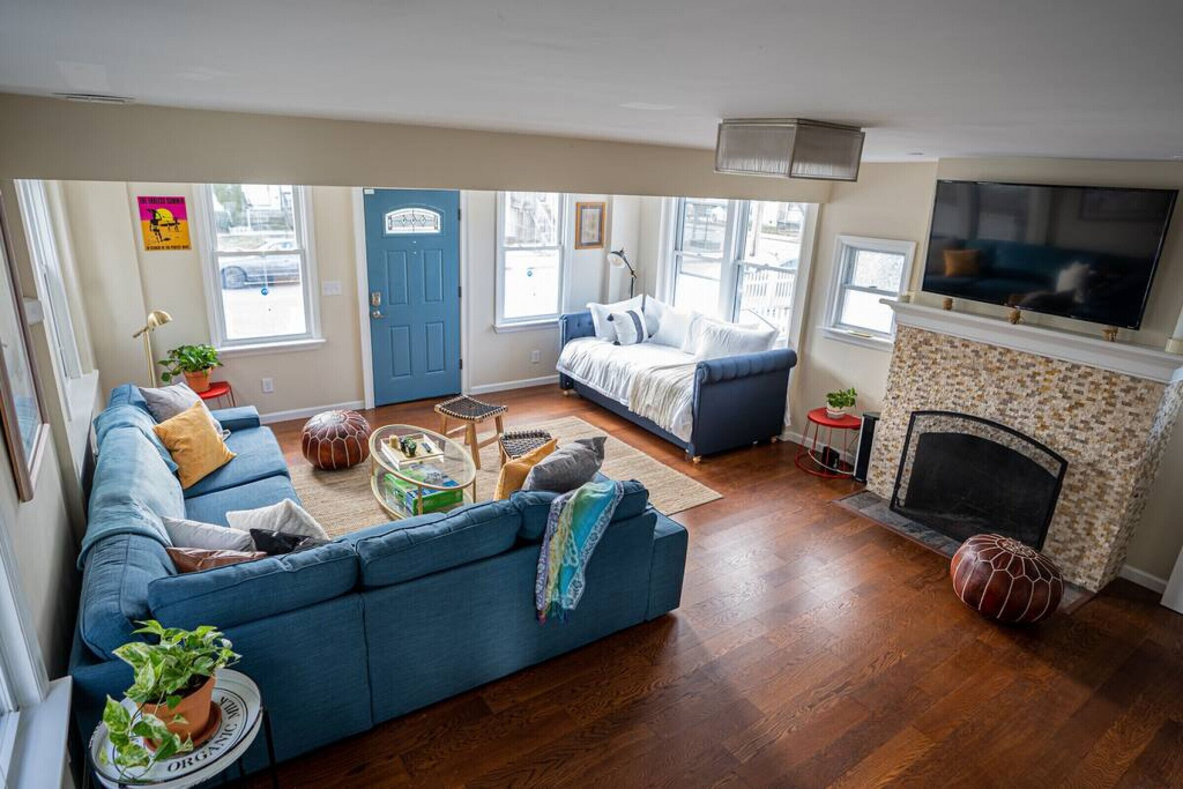 Una sala de estar con un sofá azul, una chimenea, un televisor y una puerta con marco azul.