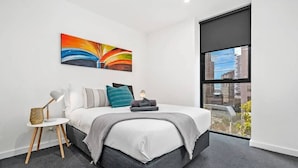 A modern bedroom with a large bed, a city view, a painting on the wall, and a small side table. - Declan - Designer Gem *Wi-Fi Views Parking (Southbank)