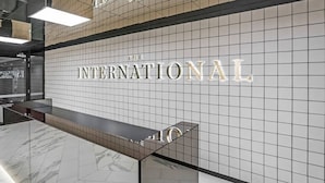 A modern interior with a tiled wall displaying 'THE INTERNATIONAL' in large letters. - Declan - Designer Gem *Wi-Fi Views Parking (Southbank)