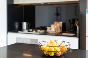 Un piano di lavoro in cucina con una ciotola metallica piena di mele e arance.