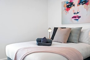 Un letto rifatto con coperte ordinate, cuscini e una lampada da comodino.