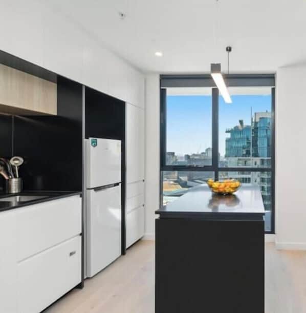 Una cucina moderna con una grande isola, elettrodomestici in acciaio inossidabile e vista sulla città attraverso ampie finestre.