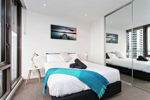 Una moderna camera d'hotel con un letto grande, un comodino, uno specchio e un dipinto raffigurante un panorama cittadino.