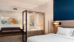 A hotel room with a bed, a sofa, a desk, and a mirror. - SpringHill Suites by Marriott Cape Canaveral Cocoa Beach (Cape Canaveral)