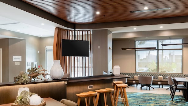 A hotel lobby with a reception desk, seating area, and a large window offering a view. - SpringHill Suites by Marriott Cape Canaveral Cocoa Beach (Cape Canaveral)