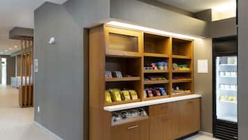 A kitchenette area with wooden cabinets, a refrigerator, and various food items.