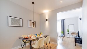 A modern dining area with a wooden table, four chairs, and a breakfast setting.