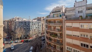 A multi-story building with balconies, a street below, and other buildings in the background.