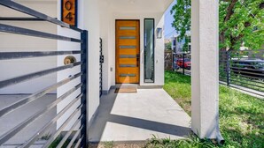 A modern entrance with a wooden door, a metal gate, and a concrete pathway leading to a building. - Mins To DT Houston / 4-Story/ 7 Beds / City Views

 (Houston)