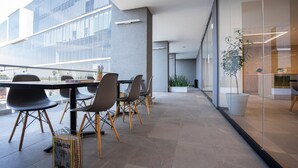A modern indoor space with a glass wall, a table with chairs, and potted plants. -  Stadía Suites Querétaro Centro Histórico (Querétaro)