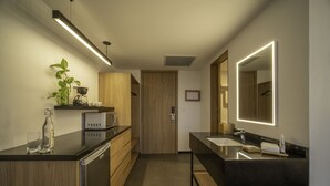 A modern kitchen with wooden cabinets, a black countertop, and a built-in coffee maker. -  Stadía Suites Querétaro Centro Histórico (Querétaro)