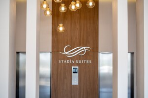 Interior de un ascensor con paneles de madera y el logotipo de 'Stadia Suites'.