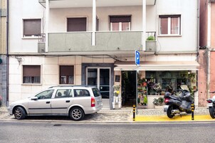 Un edificio con un cartel de estacionamiento, un coche aparcado y una motocicleta.