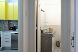 Cocina con gabinetes amarillos, lavavajillas y encimera de granito.
