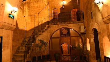 Un escalier en pierre en arc de cercle mène à un espace d’accueil où se trouvent, au premier plan, un banc et une table.