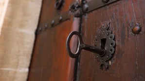 A close-up of a wooden door with a metal latch and a keyhole. - Maristan Tarihi Konak (Mardin)