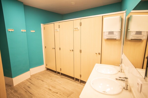 A restroom with two sinks, wooden lockers, and a mirror.
