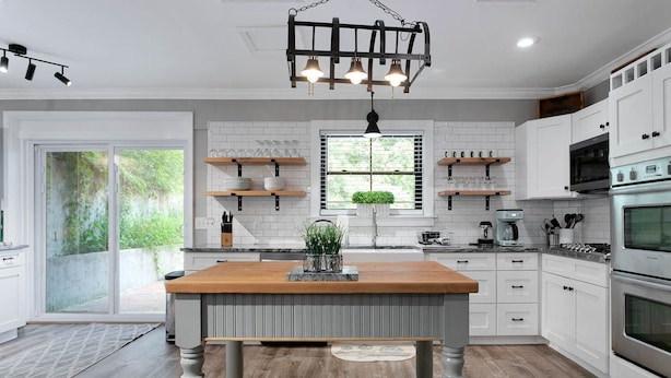 A modern kitchen with white cabinetry, a wooden island, and a hanging light fixture. - Lyric Retreat at GratiDude Ranch - Sleeps 23 with Pool in Leiper's Fork (Franklin)