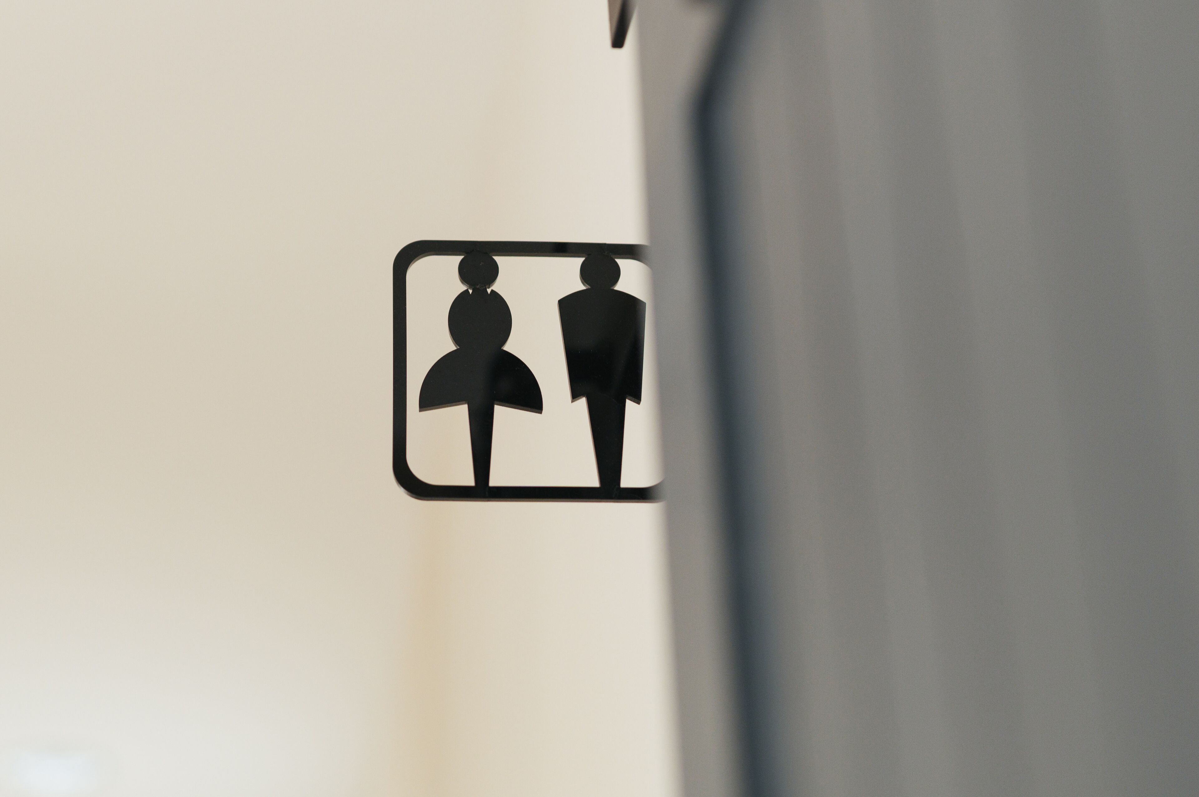 A restroom sign with symbols indicating a men's and a women's restroom.