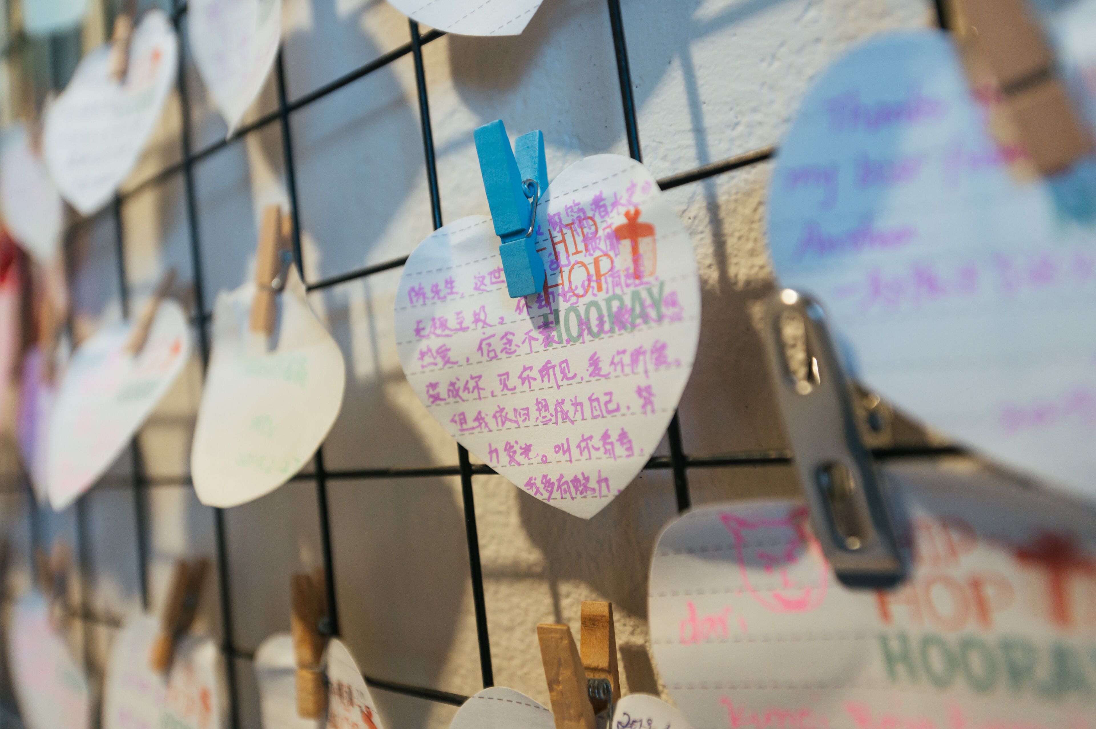 Una pared con etiquetas con forma de corazón colgando, cada una con texto manuscrito.