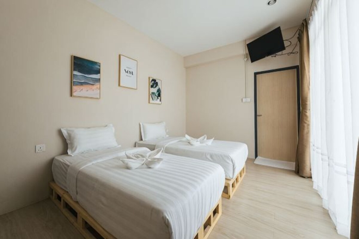 A hotel room with two beds, a flat-screen TV, and artwork on the wall.