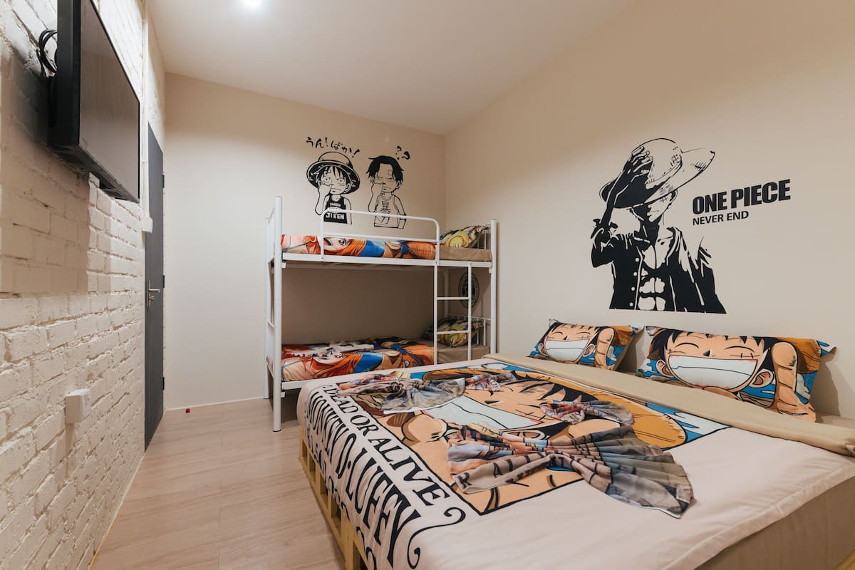 Una habitación con una litera, una cama con ropa de cama temática de anime y una pared decorada con pósters de anime.