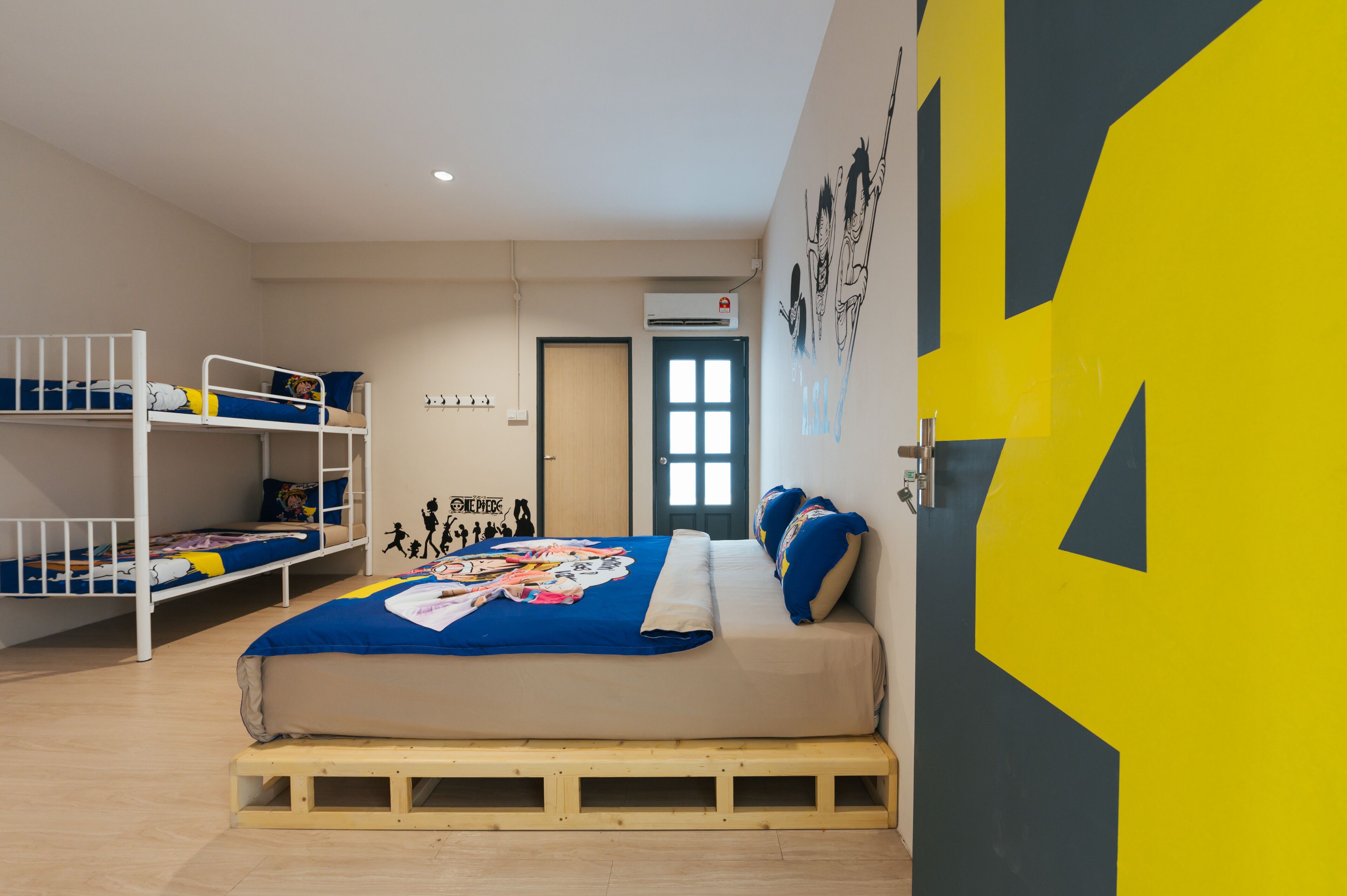 Una camera del dormitorio con letti a castello, un letto con coperta colorata e una porta con motivo geometrico.