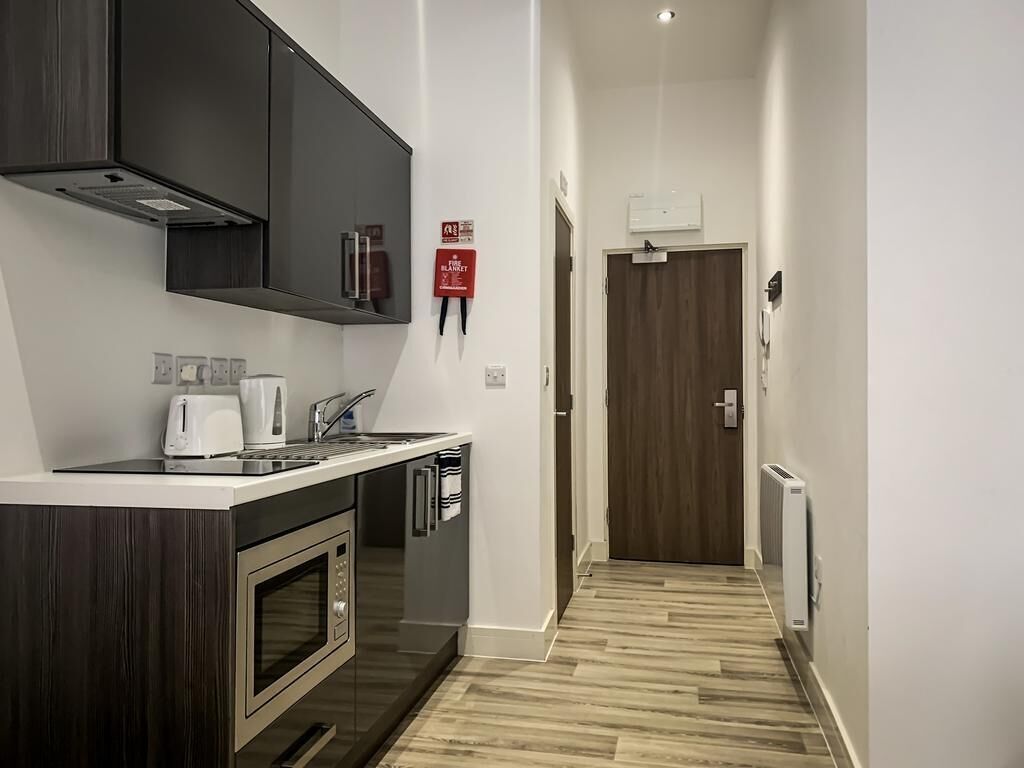 A modern kitchen with dark cabinets, a microwave, a toaster, and a red fire extinguisher.