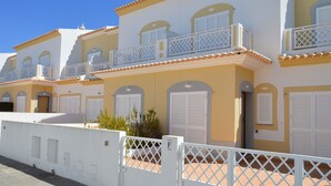 A row of yellow buildings with white balconies and shutters.