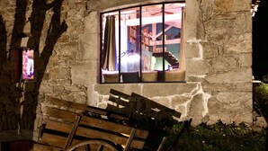 Un bâtiment en pierre avec une fenêtre donnant sur un escalier et une pièce où se trouve un lit.