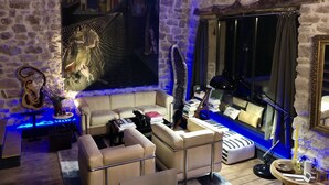 Une pièce chaleureuse avec des murs en pierre, un grand tableau, un canapé, une table basse et une fenêtre avec des rideaux.