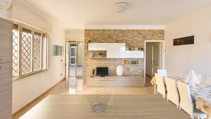 Una cocina moderna con protector mural de piedra, armarios de madera y un comedor con mesa y sillas.