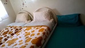Cozy retreat with a single bed featuring a brown and white spotted bedspread and a white pillow.