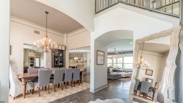 A spacious living area with a dining table, chairs, a chandelier, and a large mirror. - Luxury Lake Travis Waterfront River Retreat: pool/spa, pool table (Spicewood)