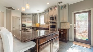 A modern kitchen with granite countertops, stainless steel appliances, and a large island. - Luxury Lake Travis Waterfront River Retreat: pool/spa, pool table (Spicewood)