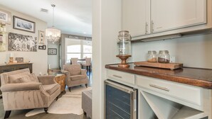 A modern kitchen with white cabinets, a wooden countertop, and a coffee maker. There are framed pictures on the wall and a chandelier hanging above the dining table. - Luxury Lake Travis Waterfront River Retreat: pool/spa, pool table (Spicewood)