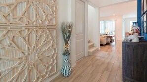 A modern interior with a geometric wooden partition, a vase with dried plants, and a staircase leading to a living area. - Brand New Home at Sonoma Resort at Tapestry (Kissimmee)