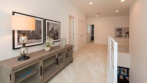 A hallway with a wooden console table, two framed pictures, and a lamp. - Brand New Home at Sonoma Resort at Tapestry (Kissimmee)