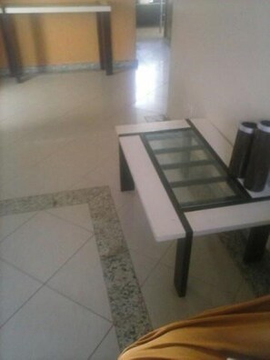 Un hall de hotel con mostrador de recepción, una mesa de vidrio y botes de basura.