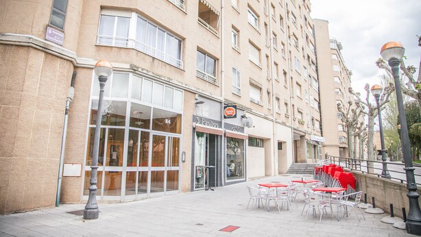 Un edificio con restaurante en la planta baja llamado "3 Pastos" y un letrero que indica "Avenida de la Salud".