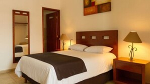 Una habitación de hotel con una cama grande, dos lámparas de noche, un espejo y un cuadro en la pared.