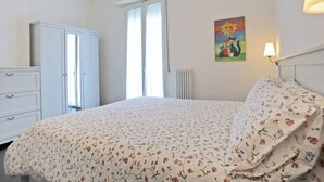 Une chambre à coucher avec un lit, une armoire, un radiateur et un tableau accroché au mur.