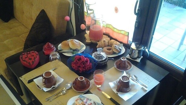 Una mesa de desayuno con diferentes alimentos, una cafetera y un calentador de té.